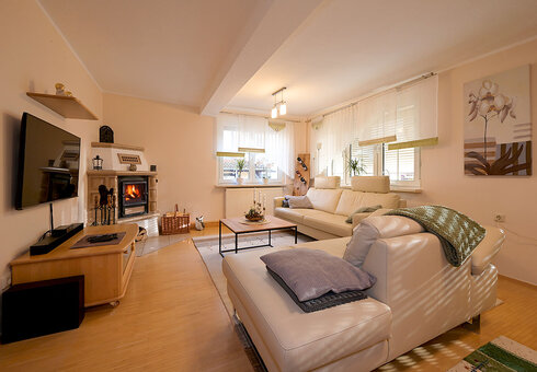 Wohnzimmer mit Couch, TV und Kamin