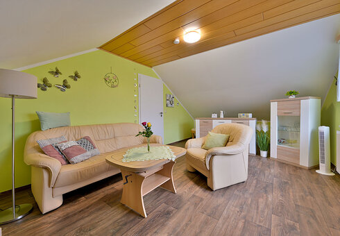 Wohnzimmer mit Couch, Sesseln und TV