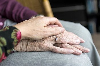 Frau hält die Hand einer alten Dame.